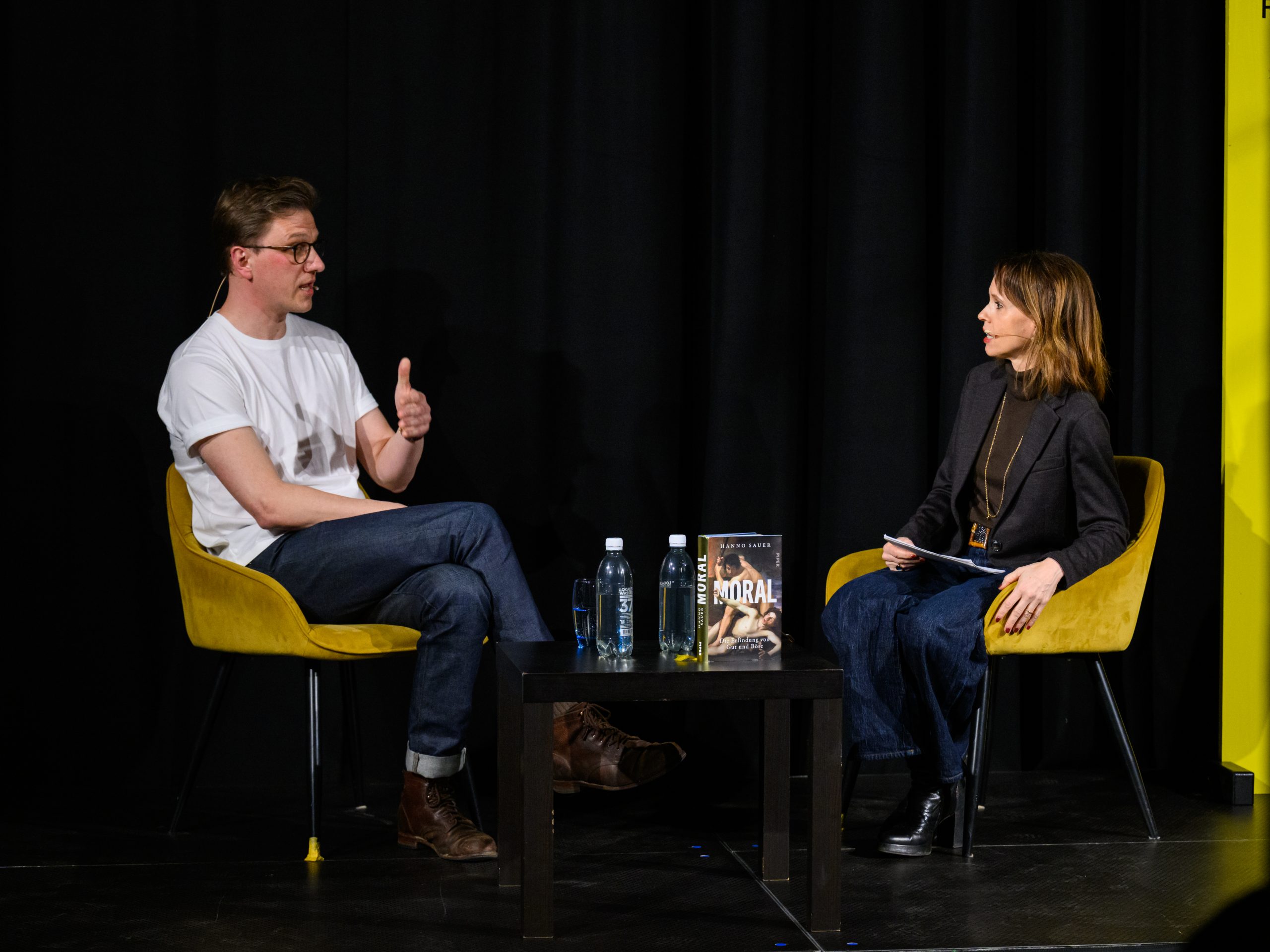 Barbara Bleisch im Gespräch bei einer Veranstaltung, sitzend in gelben Sesseln.