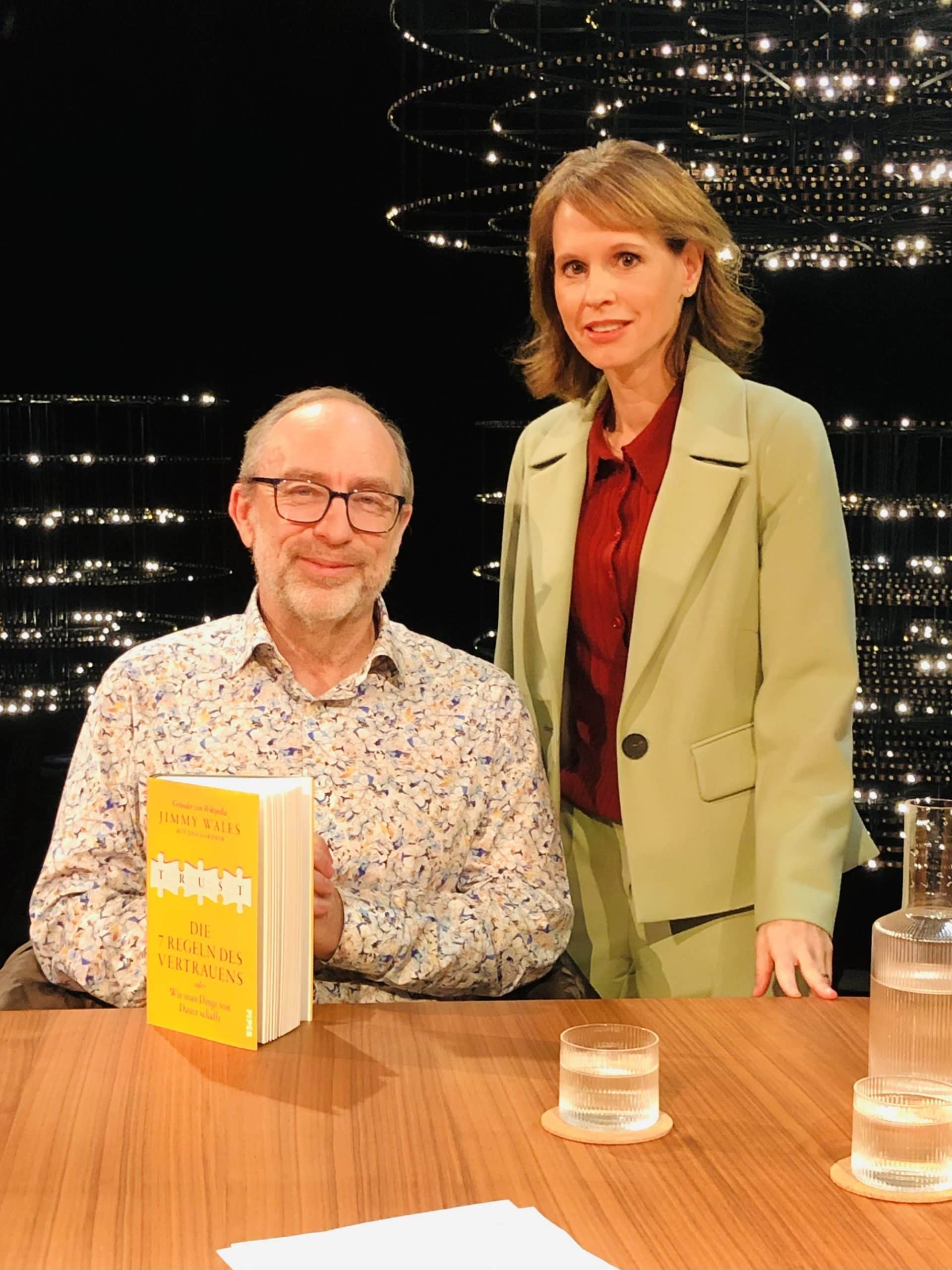 Barbara Bleisch bei einer Lesung mit einem Mann im Hintergrund.